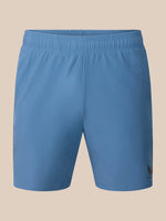 Light blue athletic shorts with an elastic waistband and a small black Castore logo on the lower left hem, shown against a solid beige background.