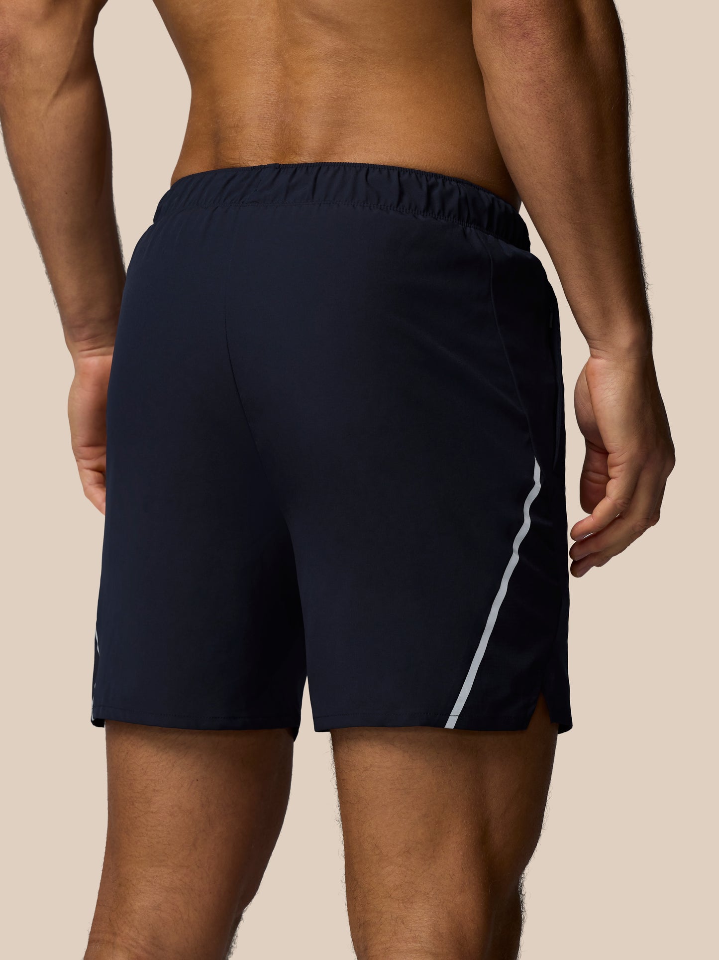 Navy blue athletic shorts with a white stripe on a beige background