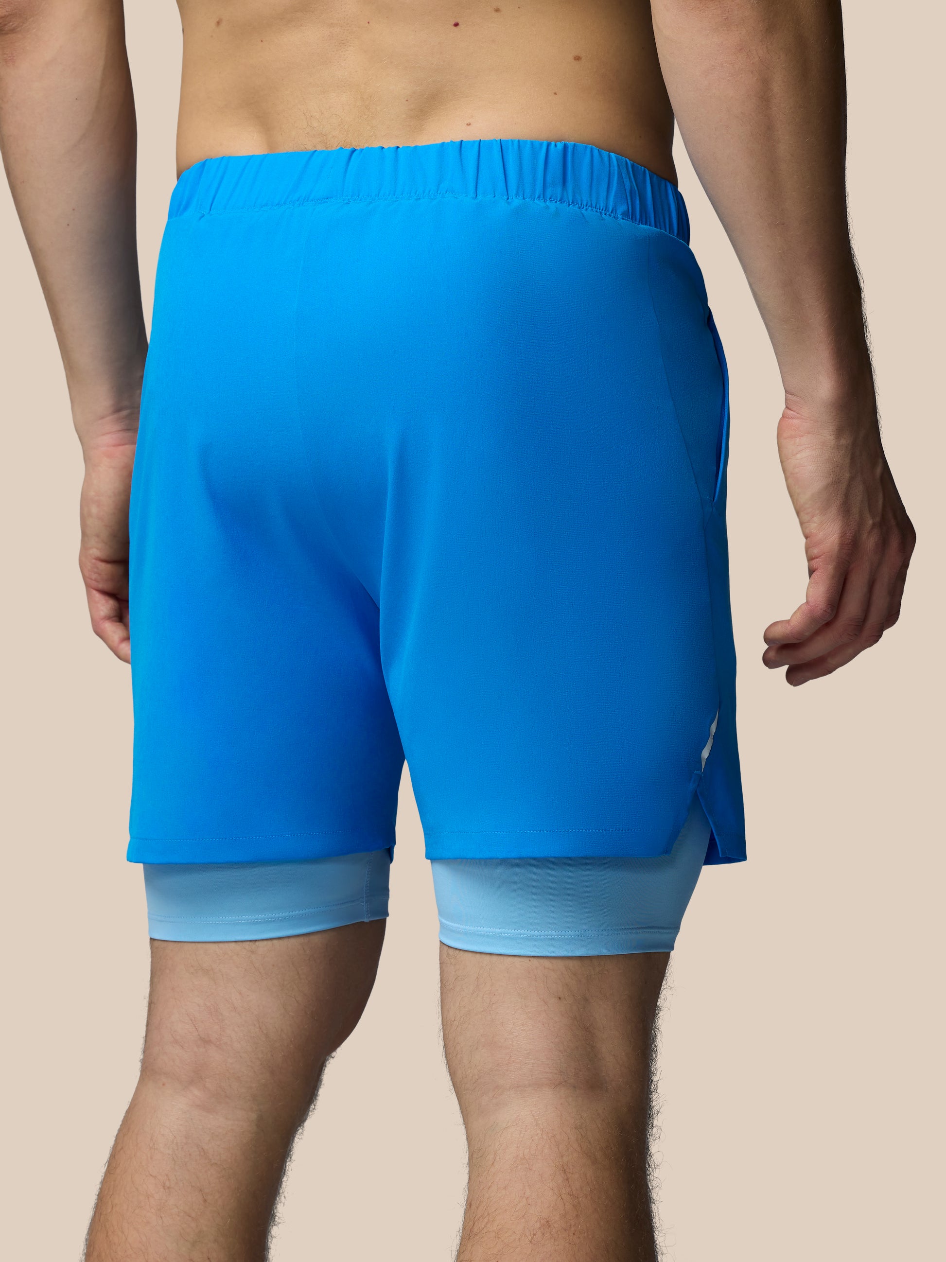 Blue athletic shorts worn by a person on a beige background
