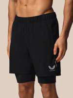 Black athletic shorts with a brand logo on a beige background