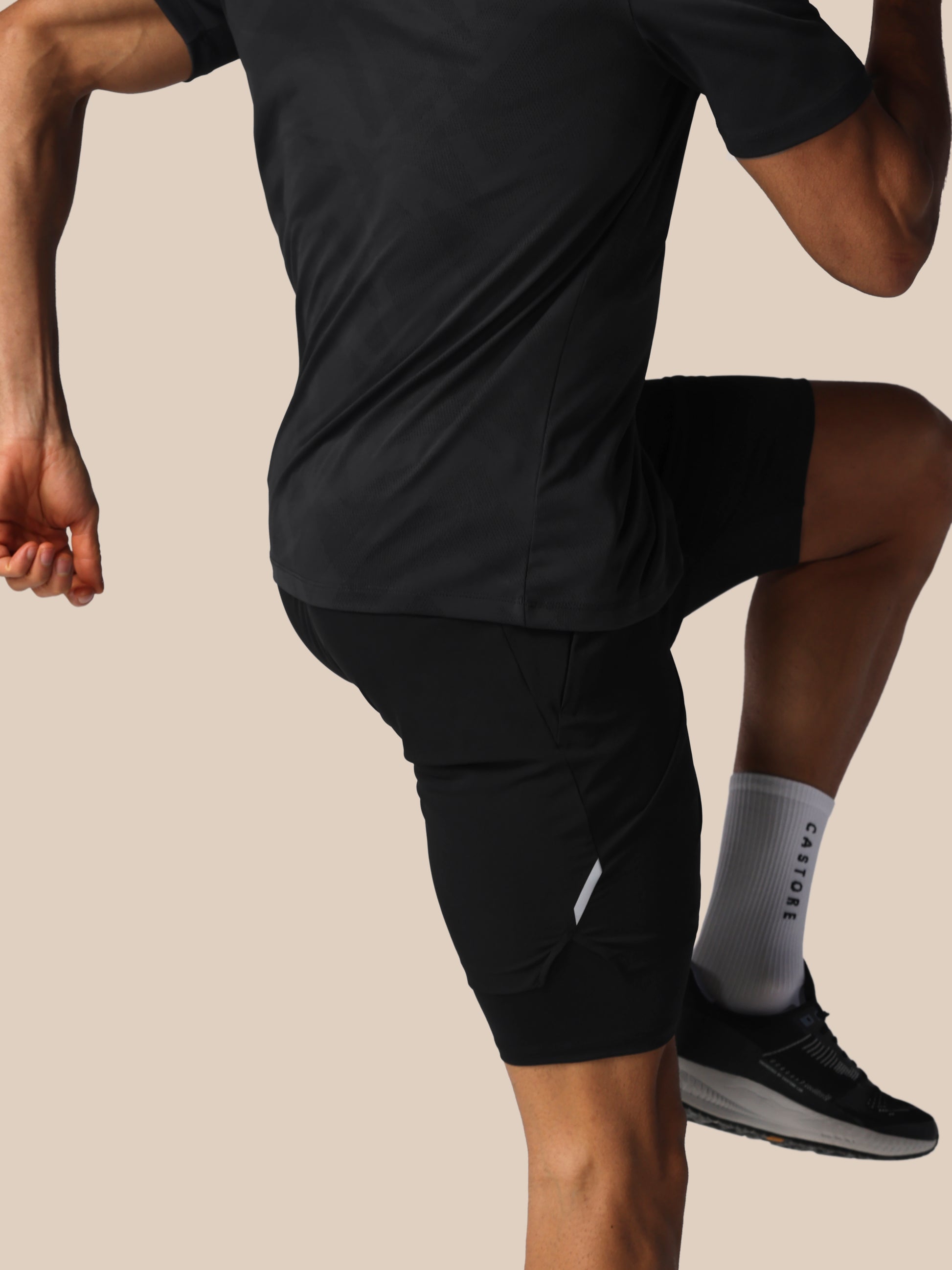 Person wearing black athletic shorts and a shirt on a beige background