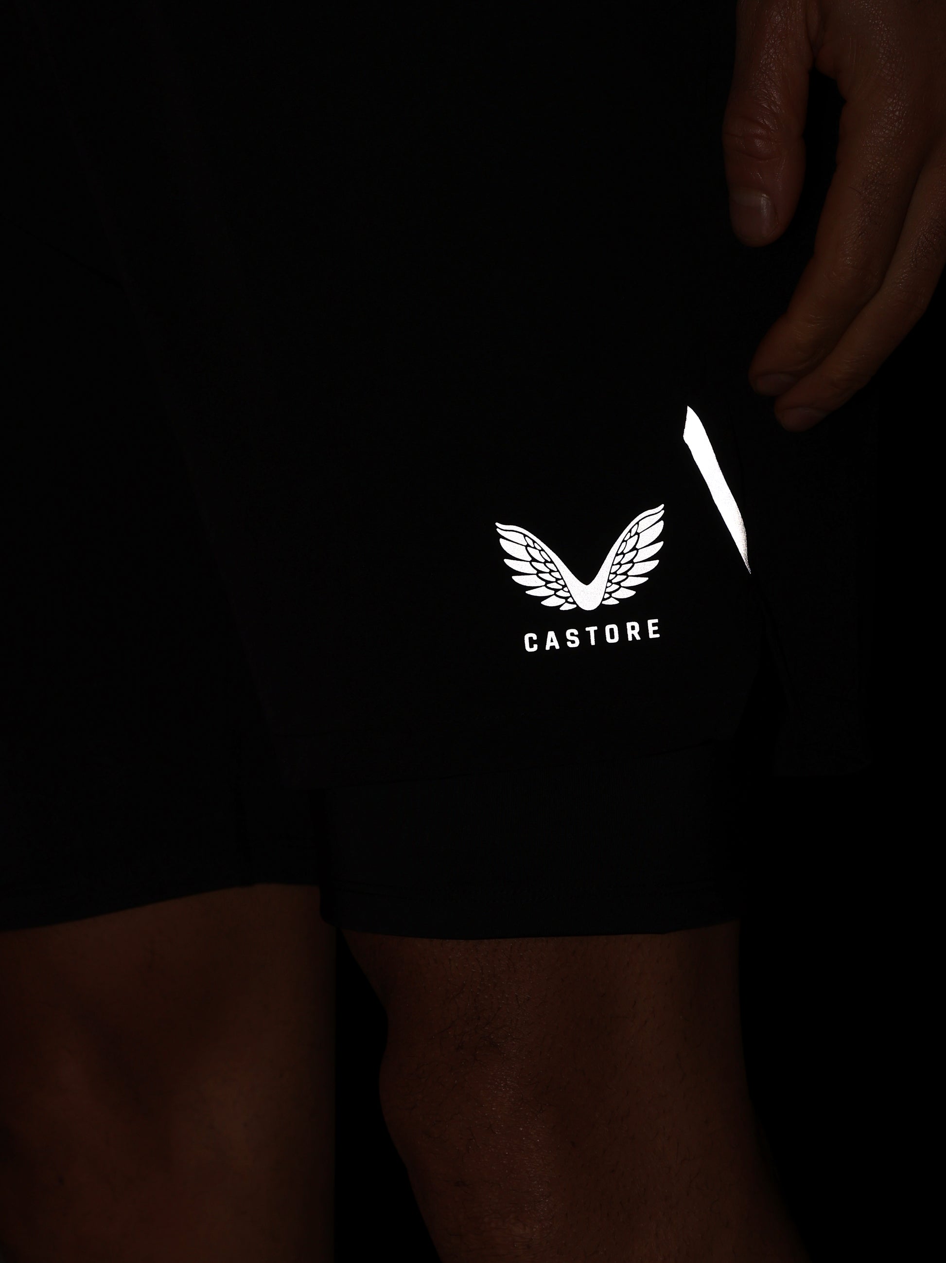Black shorts with a reflective 'Castore' logo on a dark background