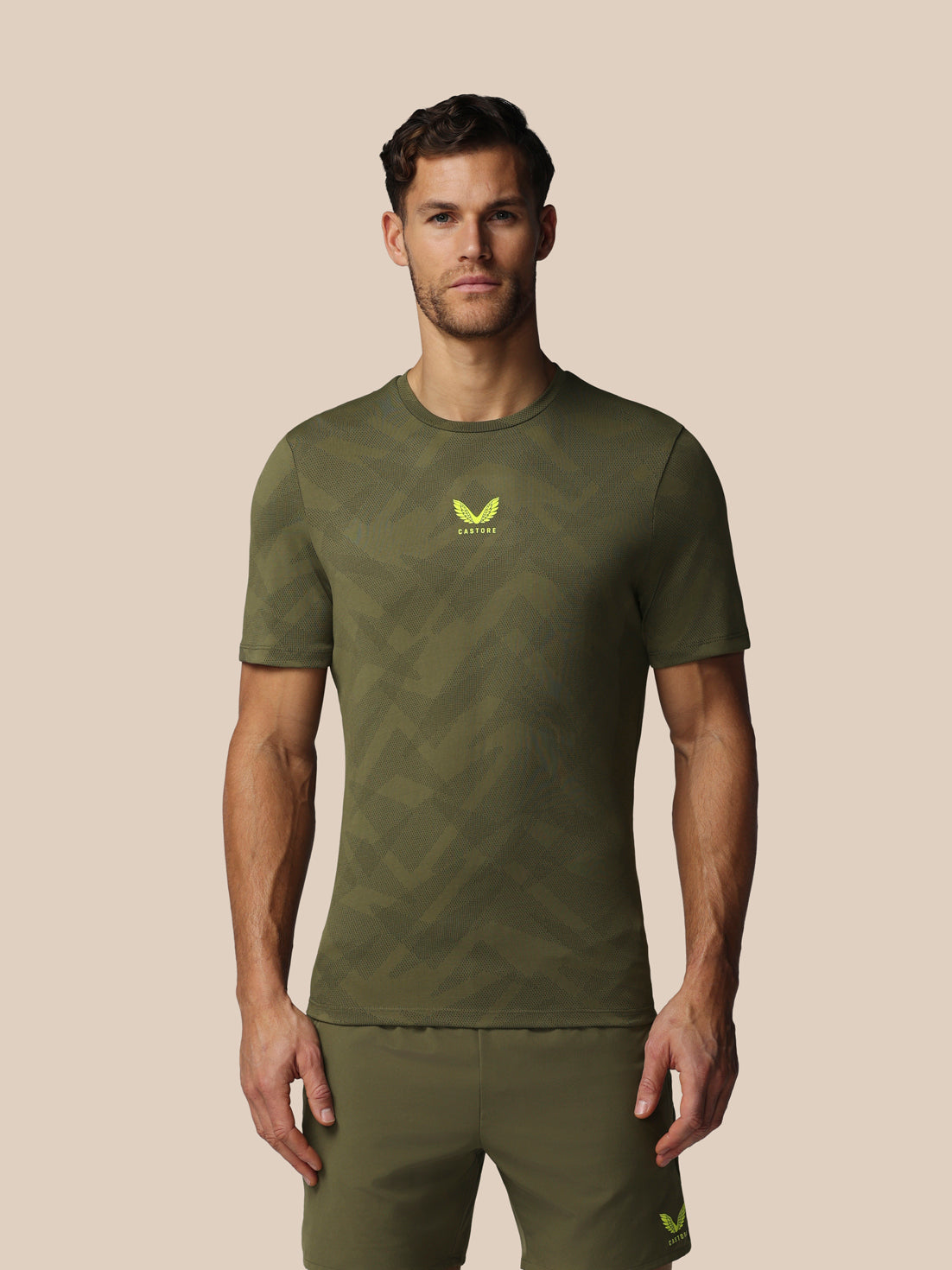 Man wearing a green athletic outfit with a logo on a beige background