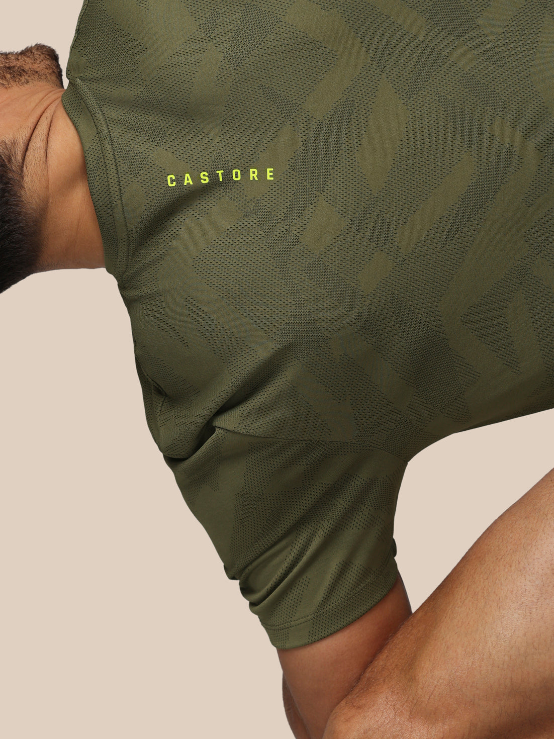 Green athletic shorts with 'Castore' branding on a beige background