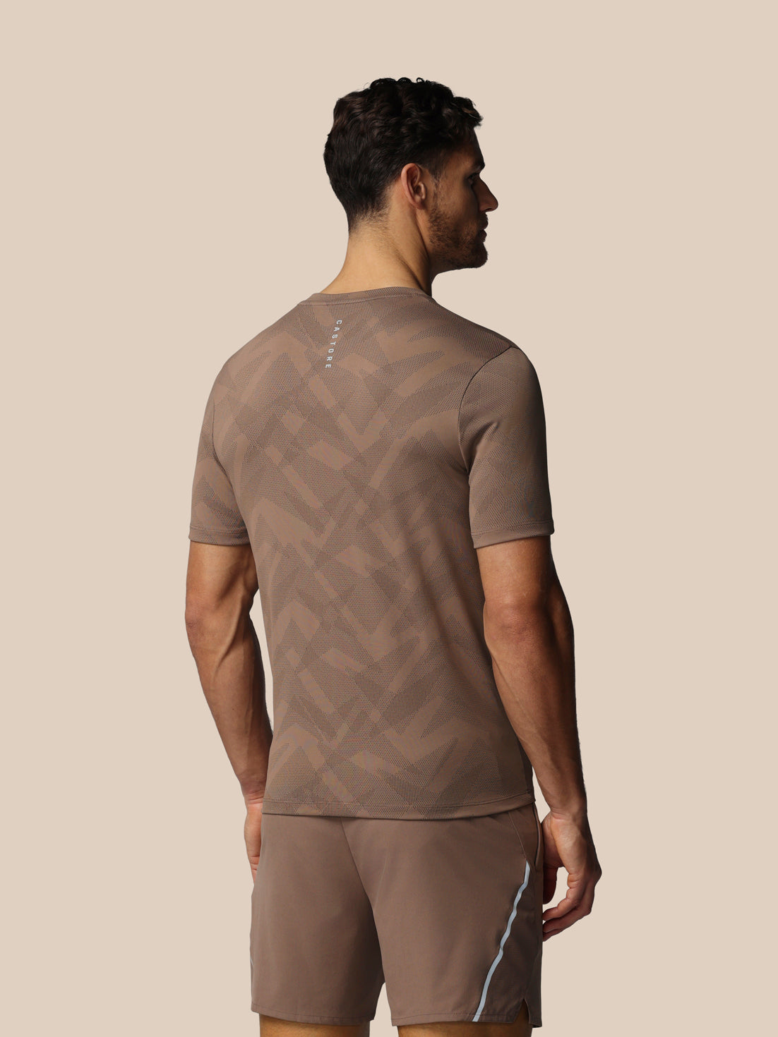 Man wearing a brown athletic outfit on a beige background