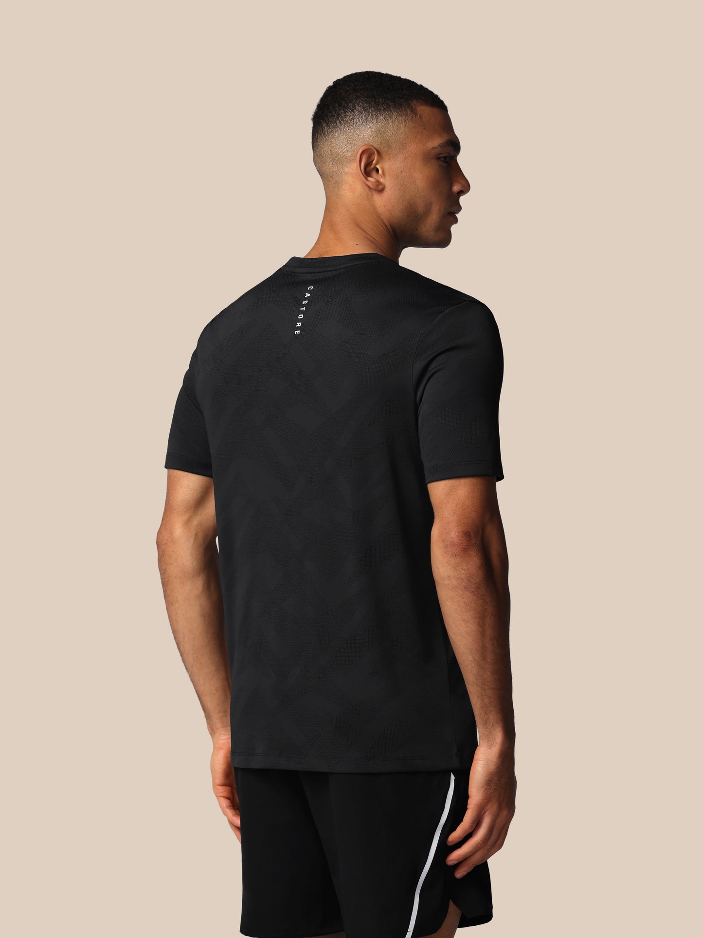 Man wearing a black t-shirt and shorts on a beige background