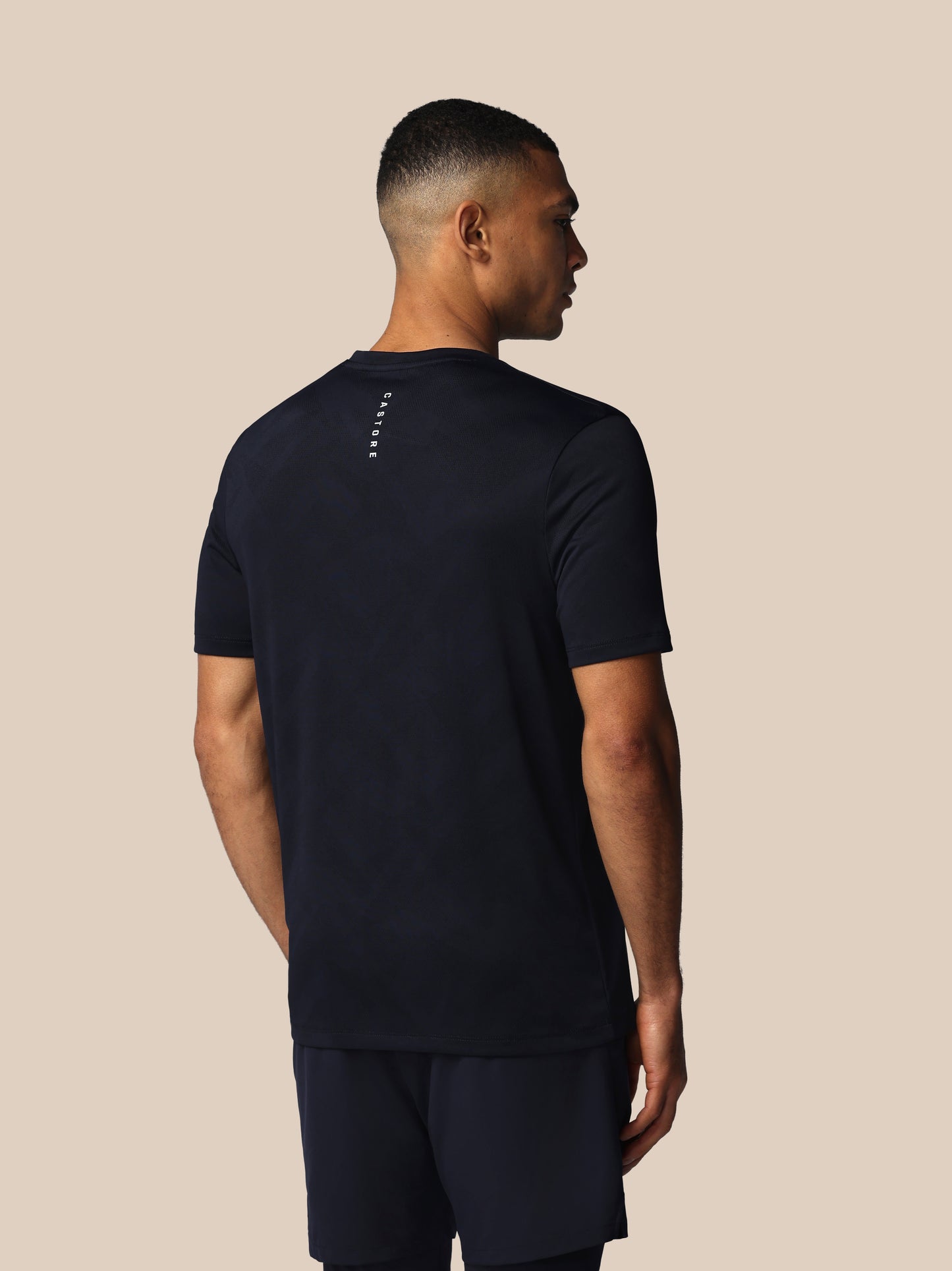 Man wearing a black t-shirt and shorts on a beige background