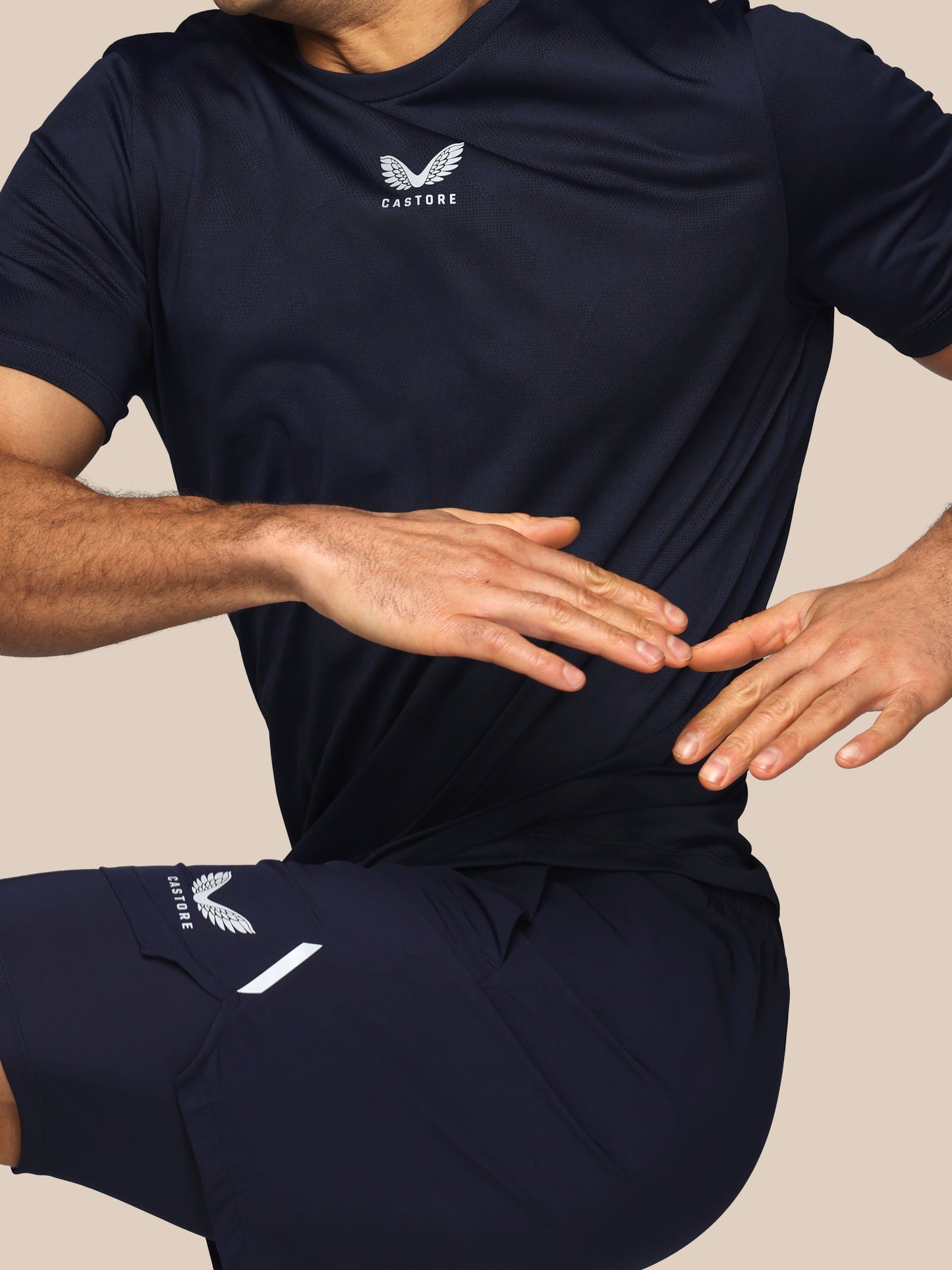 Person wearing navy athletic outfit with brand logo on a neutral background