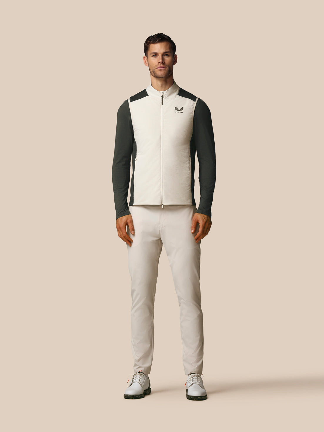 Man wearing a black and white jacket with a logo on a beige background