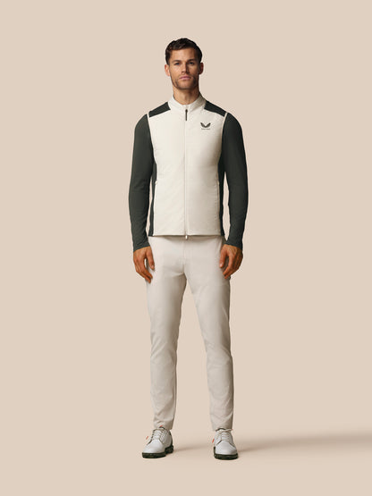 Man wearing a black and white jacket with a logo on a beige background