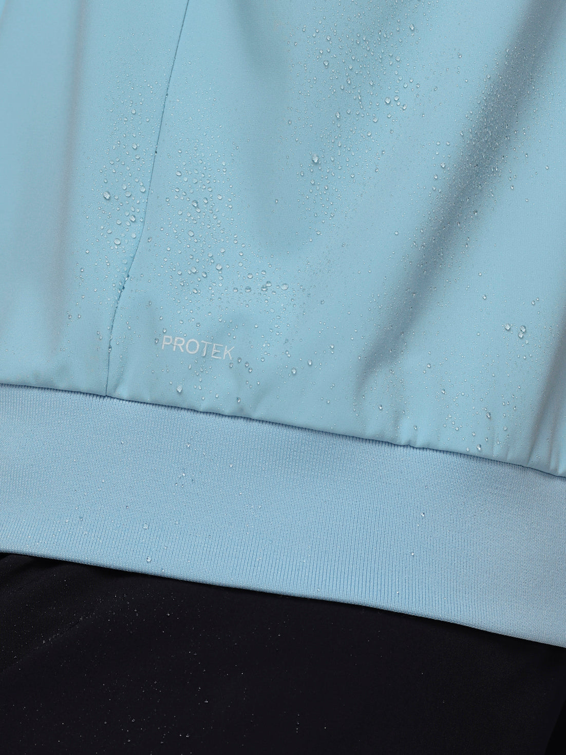 Close-up of a light blue fabric with 'PROTEK' branding.