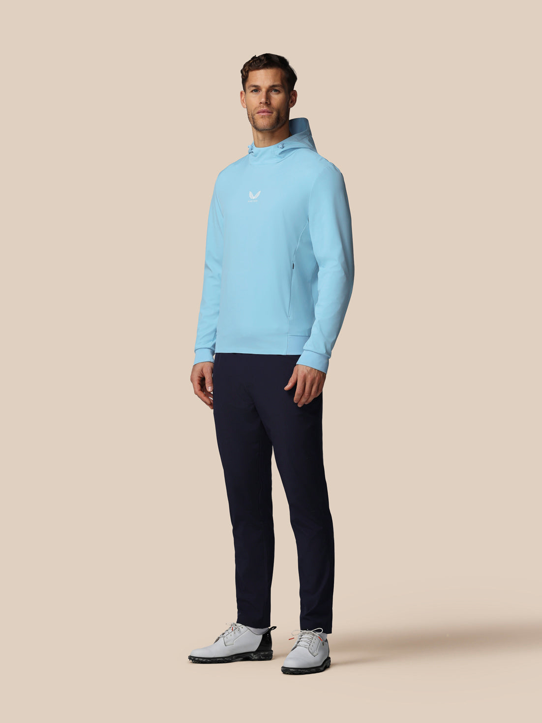 Man wearing a light blue sweater and dark pants on a beige background