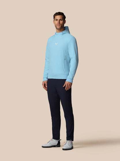 Man wearing a light blue sweater and dark pants on a beige background