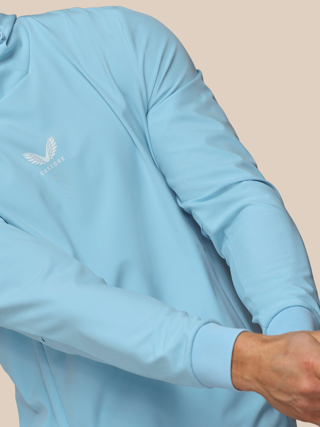 Light blue long-sleeve shirt with a brand logo on a beige background
