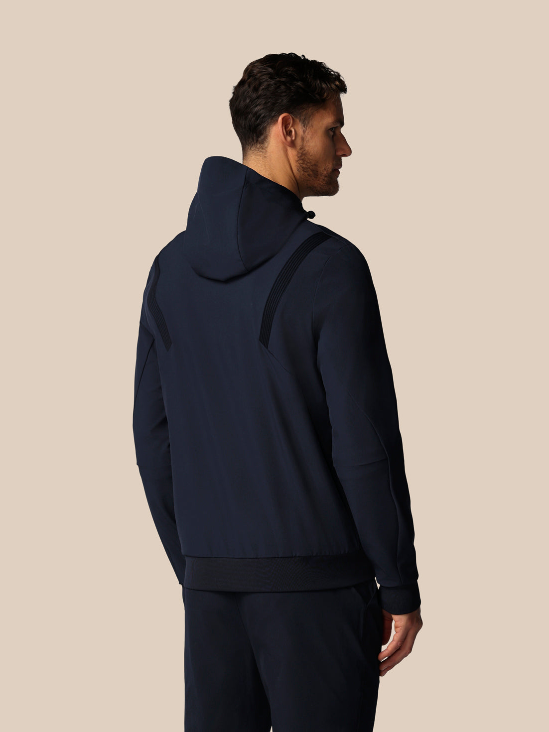 Man wearing a navy blue hoodie and pants on a beige background