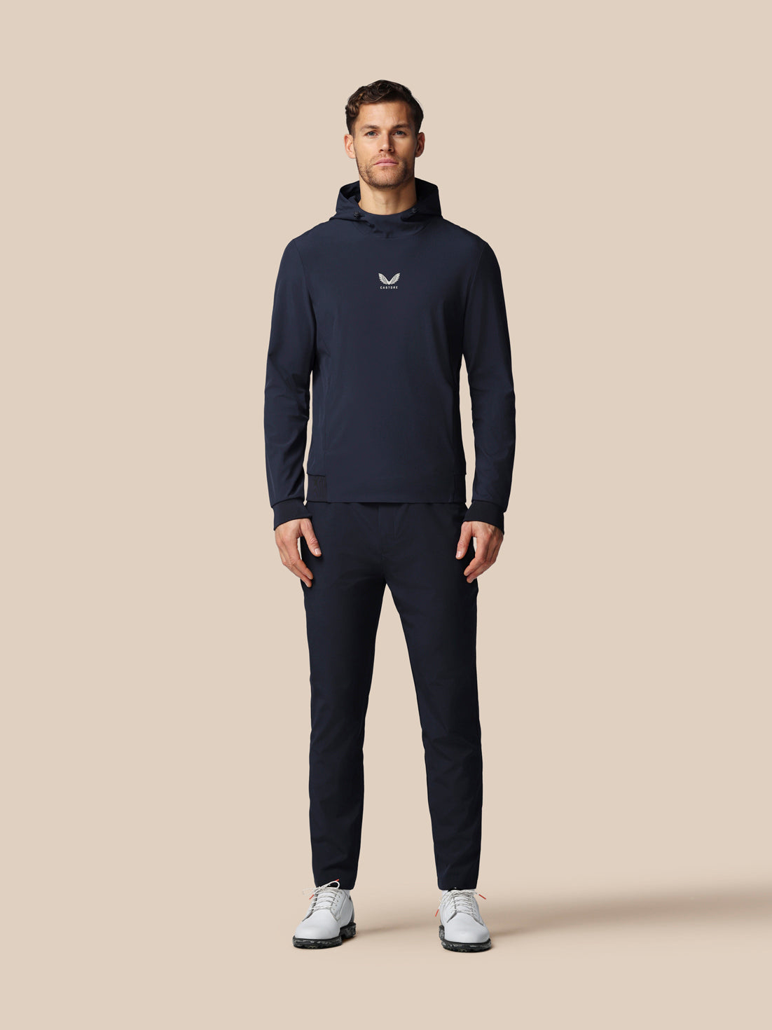 Man wearing a navy tracksuit with a logo on a beige background