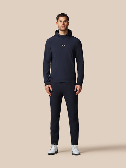 Man wearing a navy tracksuit with a logo on a beige background