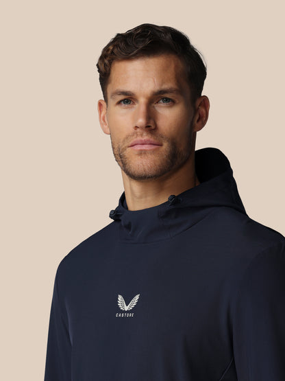 Man wearing a navy hoodie with a logo on a beige background
