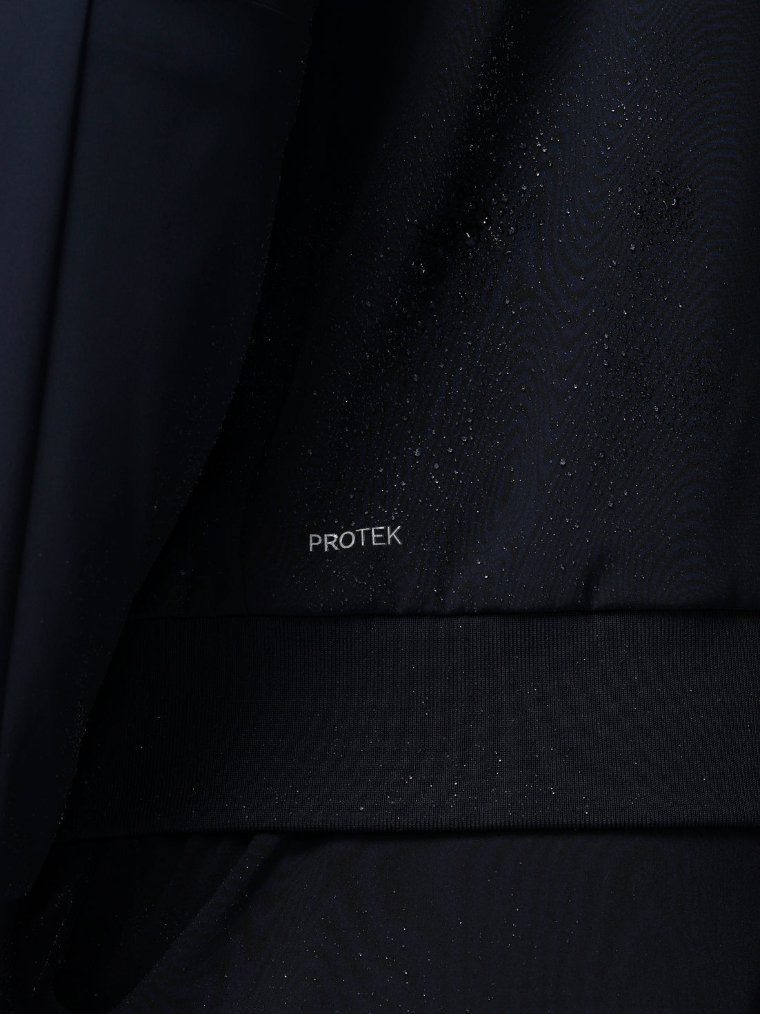 Close-up of a black fabric with 'PROTEK' branding.