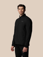 Man wearing a black jacket with a logo on a beige background