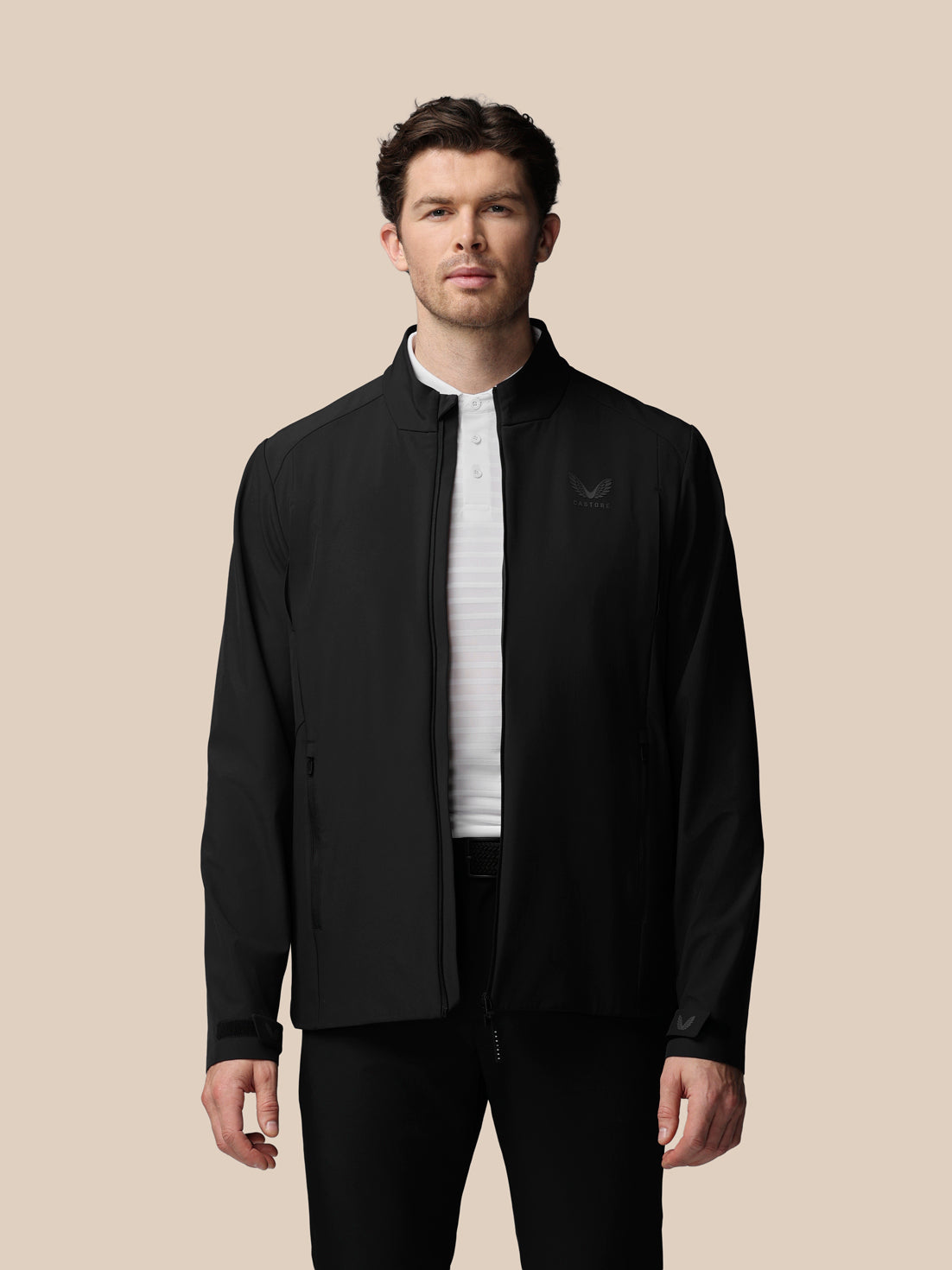 Man wearing a black jacket with a brand logo on a beige background