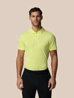Man wearing a bright yellow polo shirt with a logo on a beige background