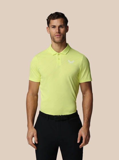 Man wearing a bright yellow polo shirt with a logo on a beige background