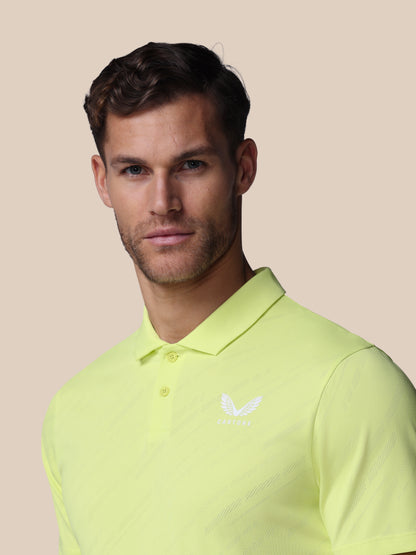 Man wearing a light green polo shirt with a brand logo on a beige background