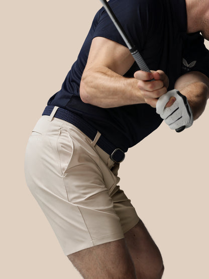 Person in golf attire holding a club on a beige background