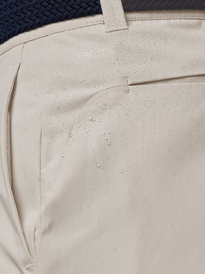 Close-up of beige pants with decorative elements and 'PROTEK' branding.