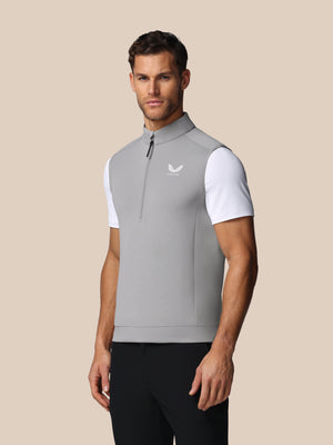 Man wearing a gray and white sleeveless shirt with a Castore logo on a beige background