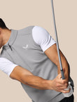 Person wearing a gray Castore shirt holding a golf club on a beige background