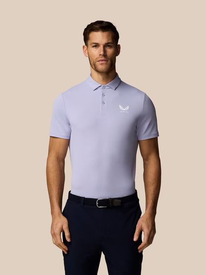 Man wearing a light purple polo shirt with a logo on a beige background