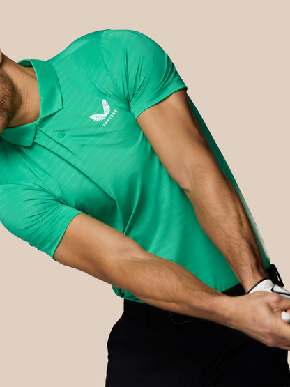 Person wearing a green polo shirt with a logo on a beige background