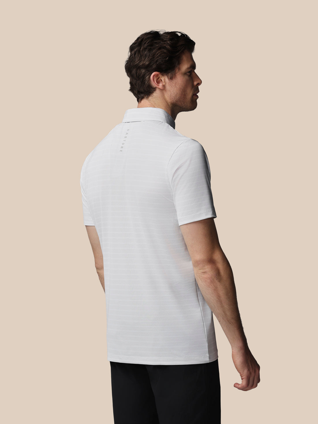 Man wearing a white polo shirt against a beige background