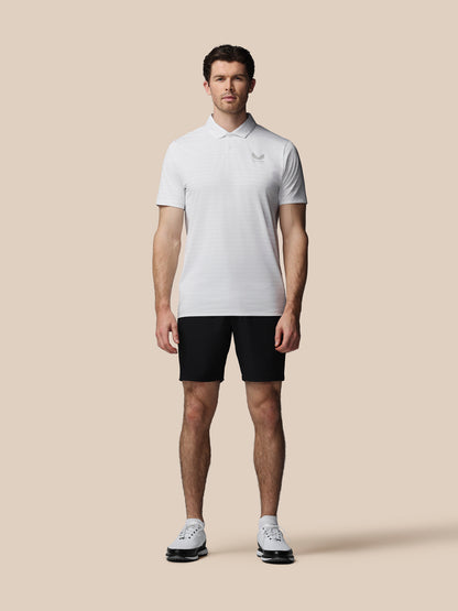 Man wearing a white polo shirt and black shorts on a beige background