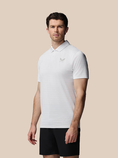 Man wearing a white polo shirt with a logo on a beige background