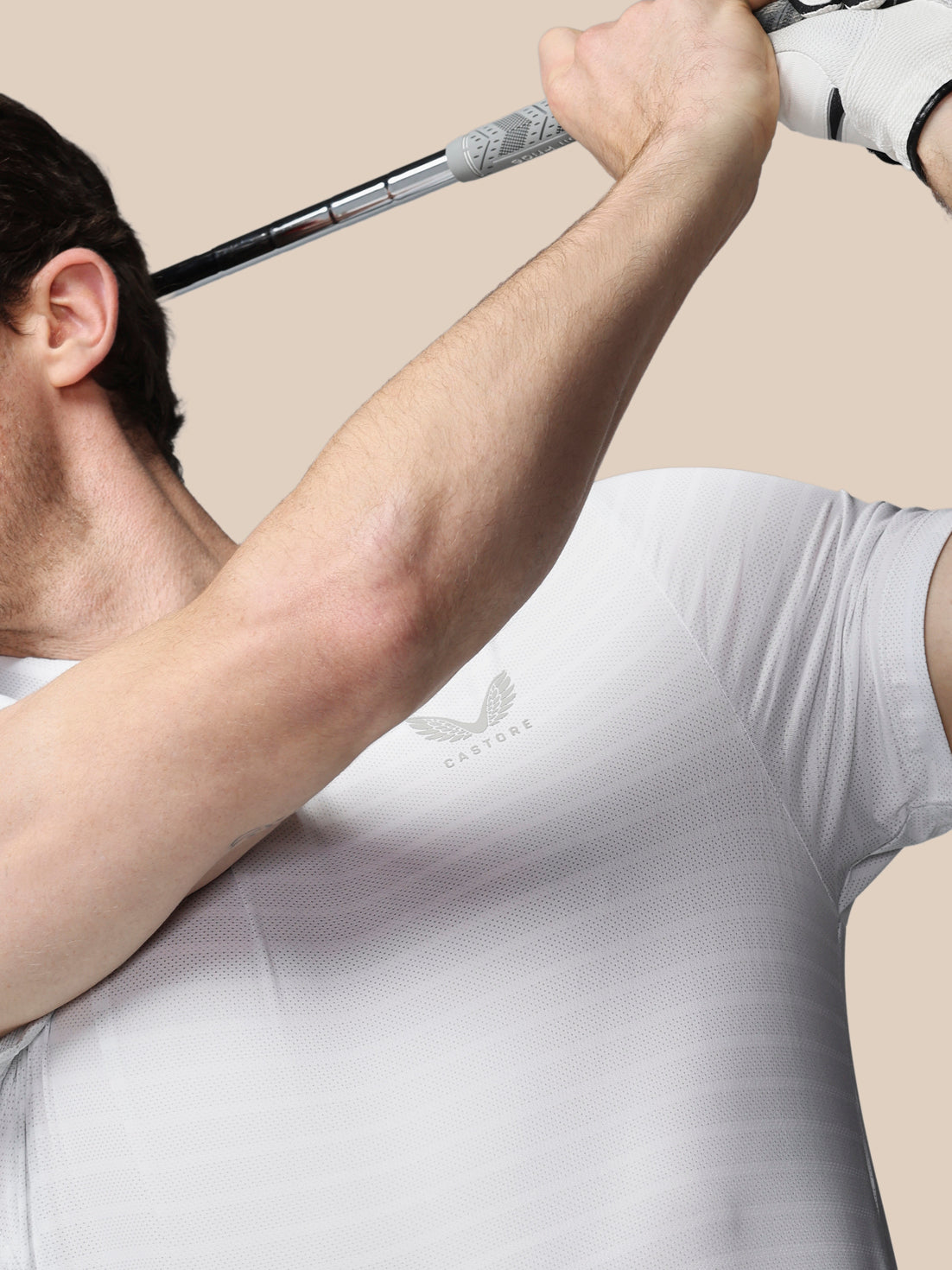 Person in a white shirt holding a golf club with a beige background