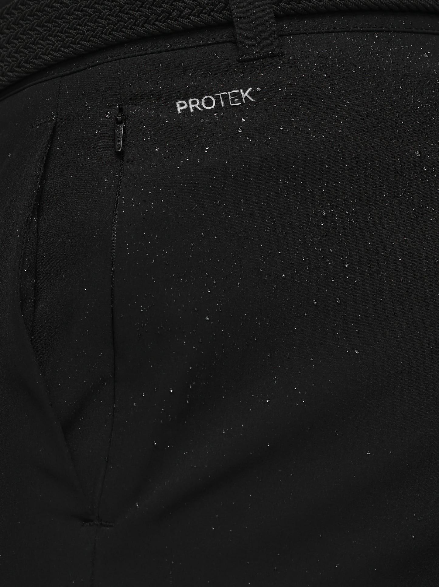 Close-up of a black jacket with 'PROTEK' branding on a textured background