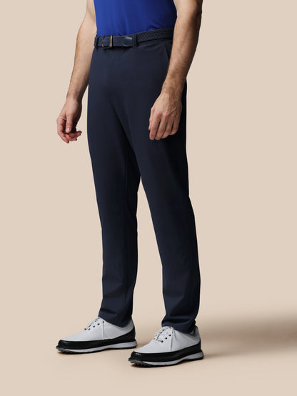 Person wearing navy pants and a blue shirt on a beige background