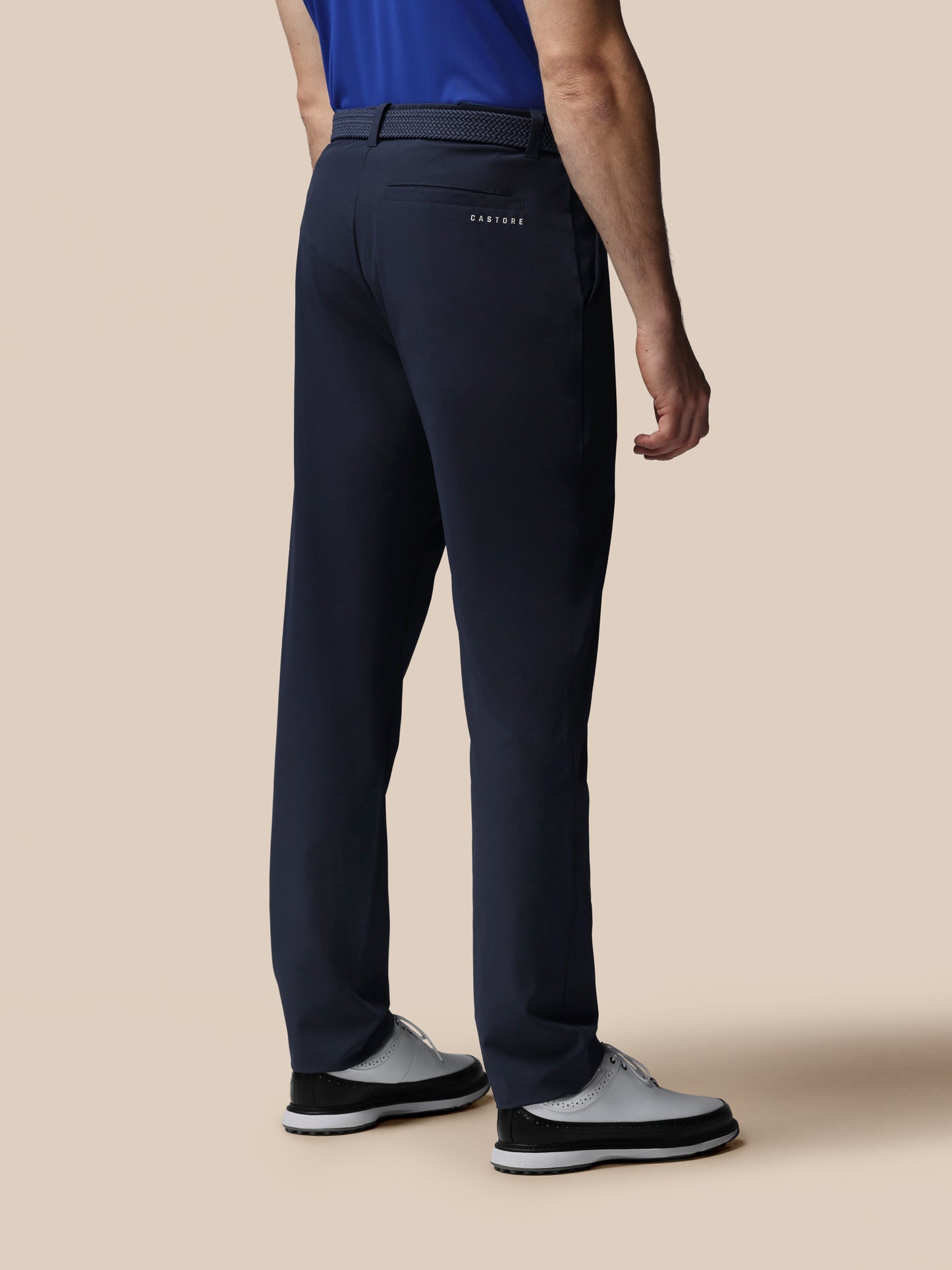 Person wearing navy pants with a visible brand logo on a beige background