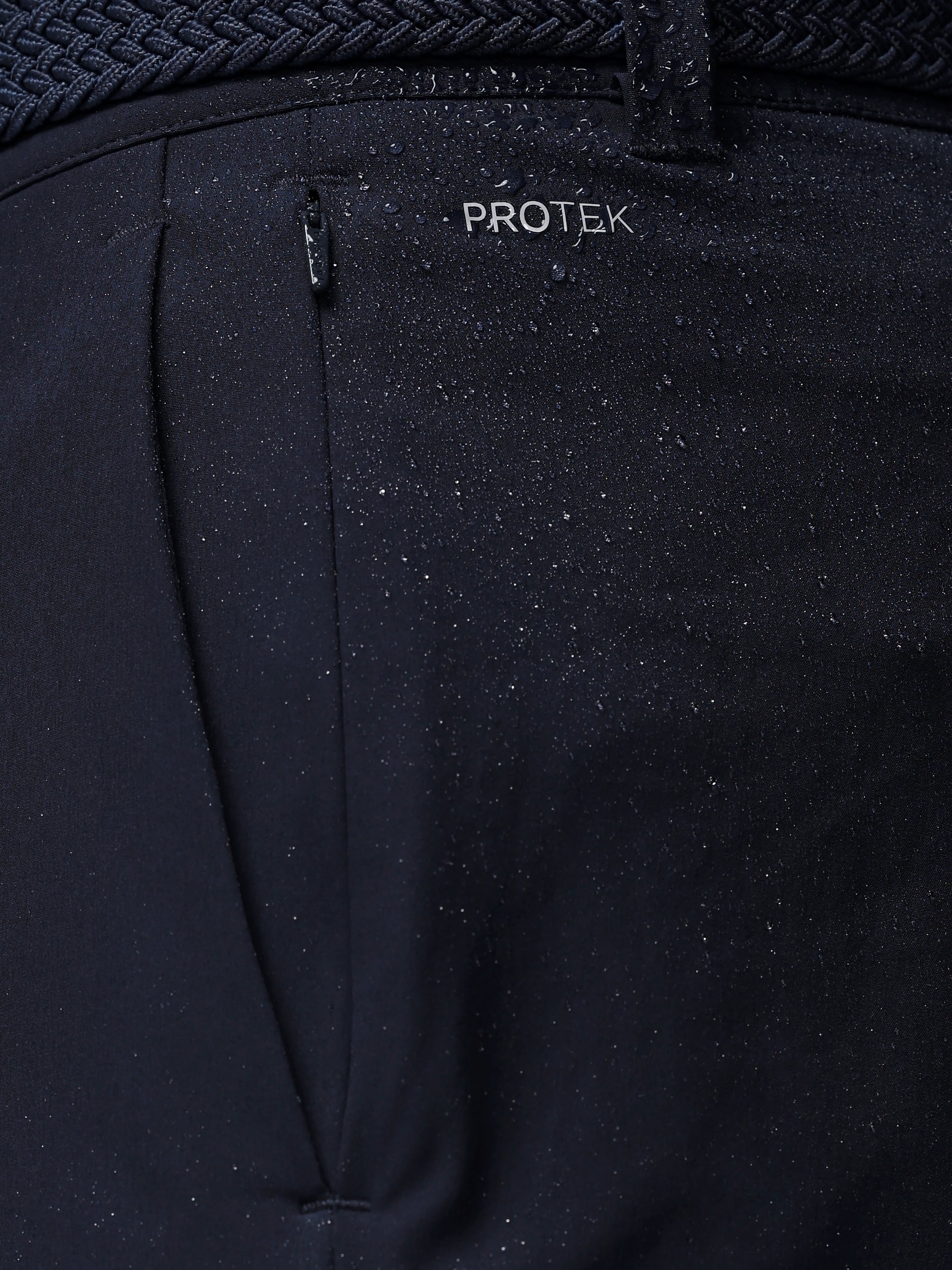Black pants with a visible 'PROTEK' brand logo on a dark background