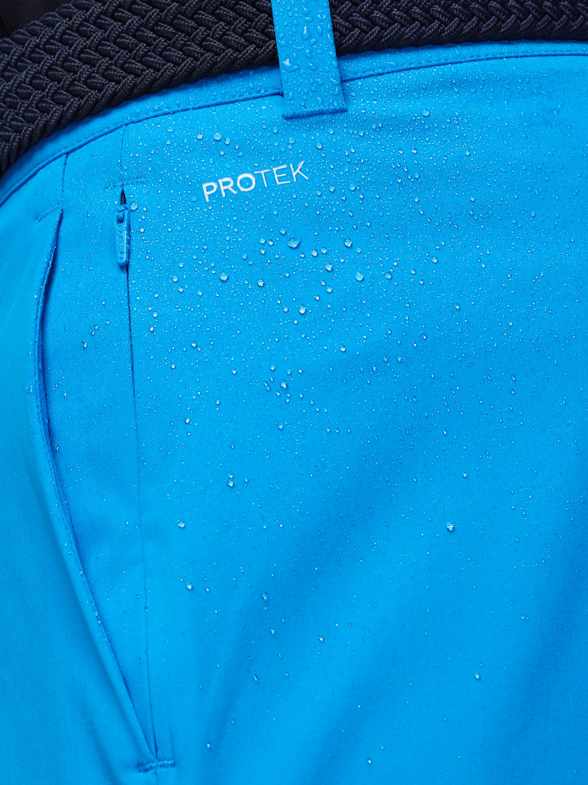Blue jacket with 'PROTEK' branding showing water droplets on the fabric.