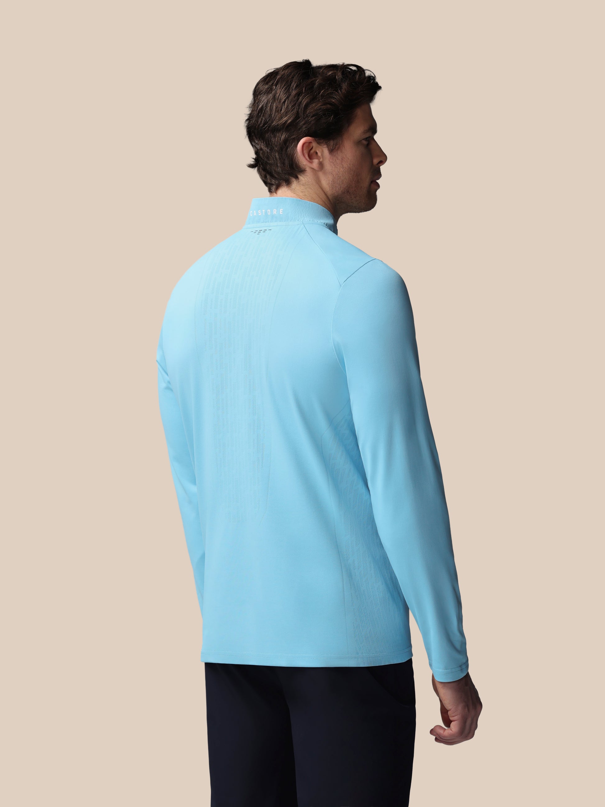 Man wearing a light blue long-sleeve shirt against a beige background