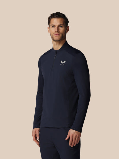 Man wearing a navy long-sleeve shirt with a logo on a beige background