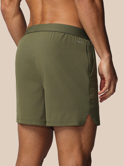 Person wearing green athletic shorts on a beige background