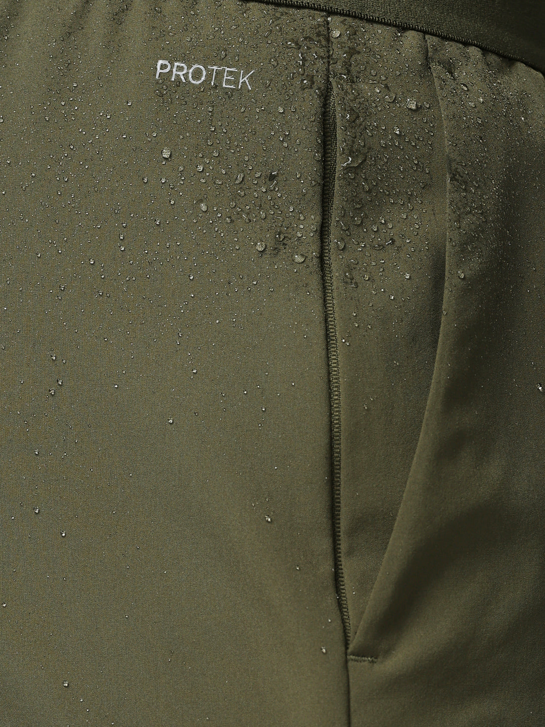 Close-up of a green jacket with 'PROTEK' branding on a textured surface.
