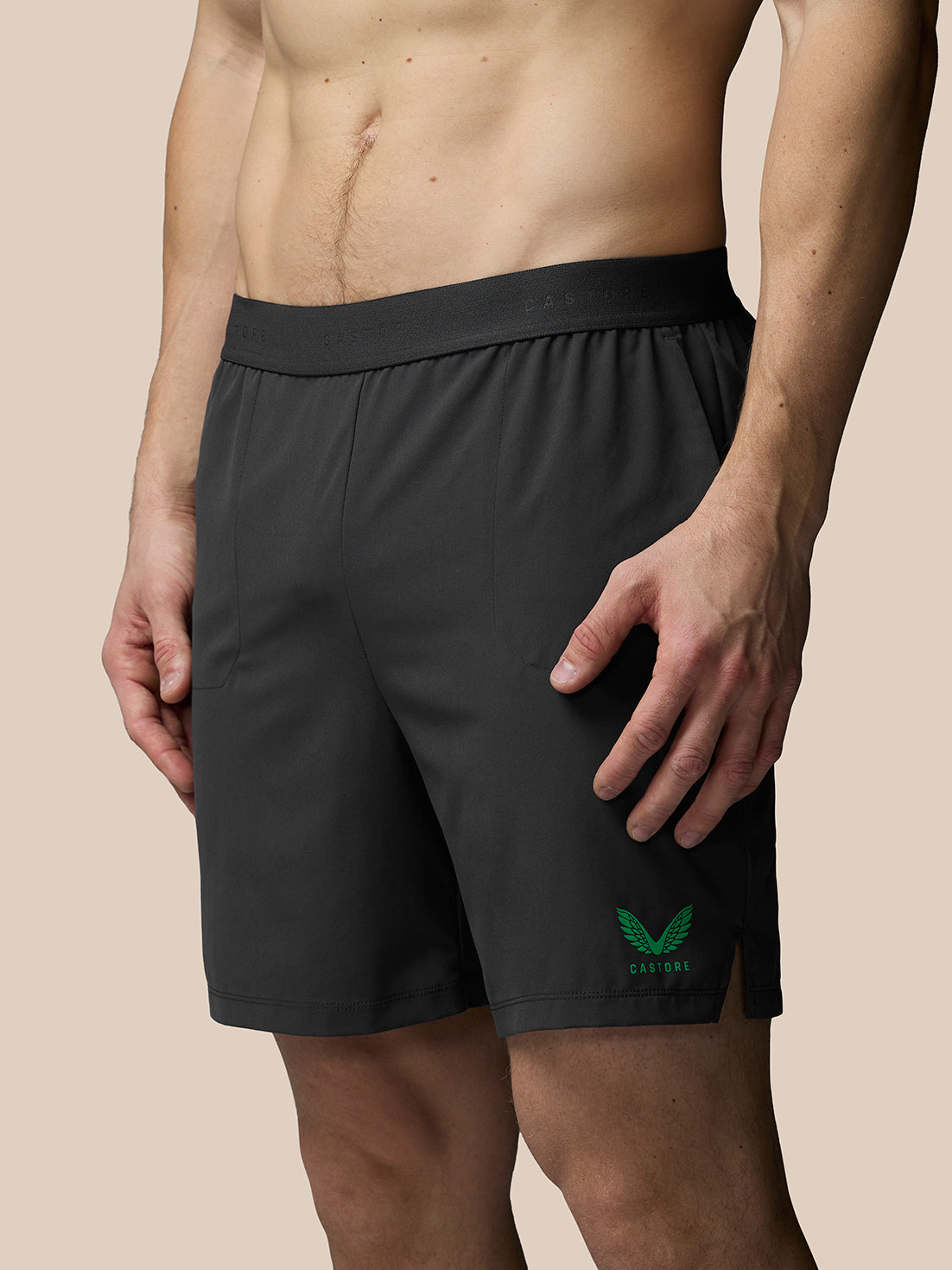 Black athletic shorts with a green logo on a beige background