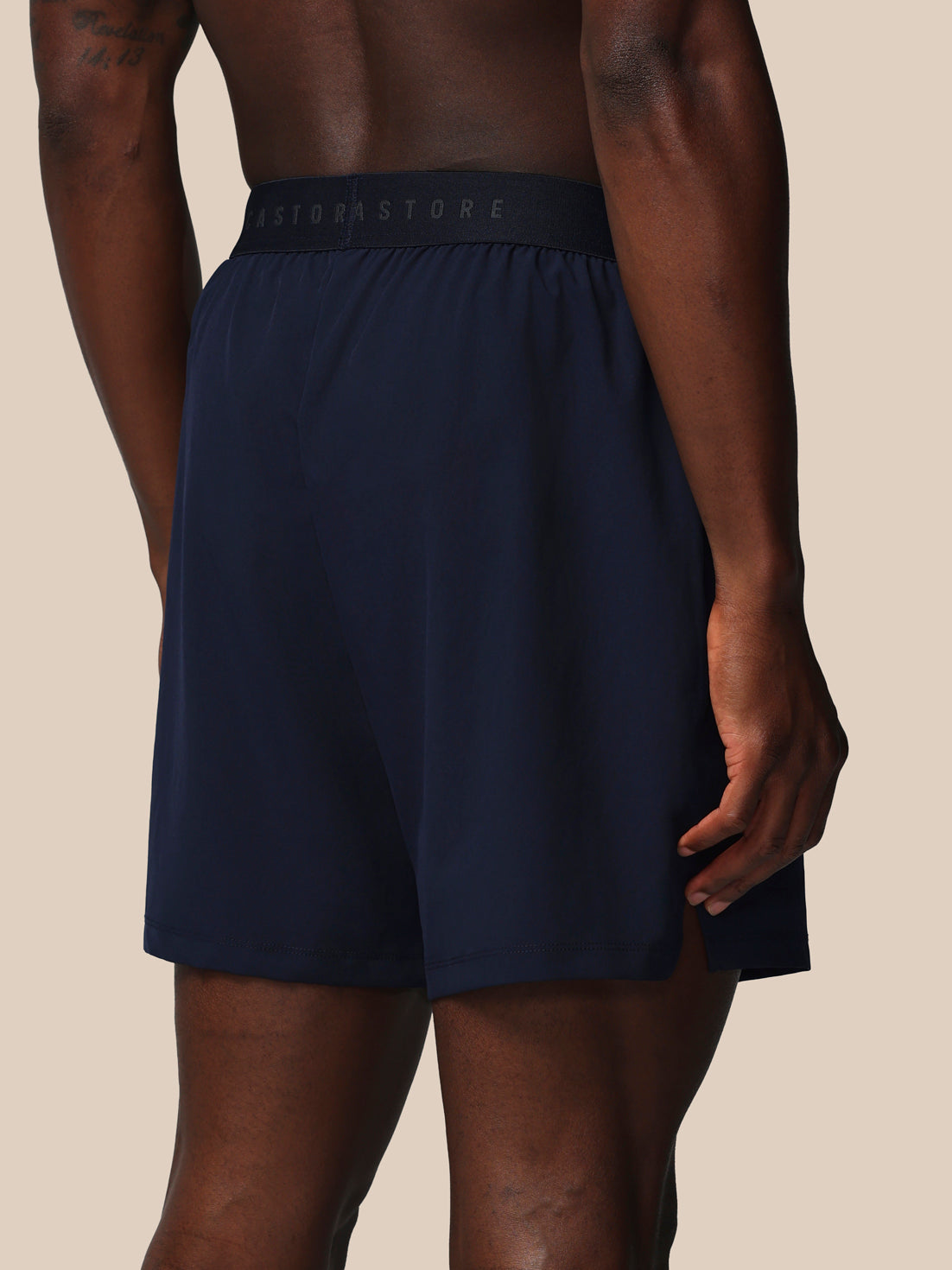 Navy blue athletic shorts with a brand logo on the waistband against a beige background