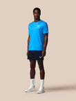 Man wearing a blue athletic shirt and black shorts on a beige background
